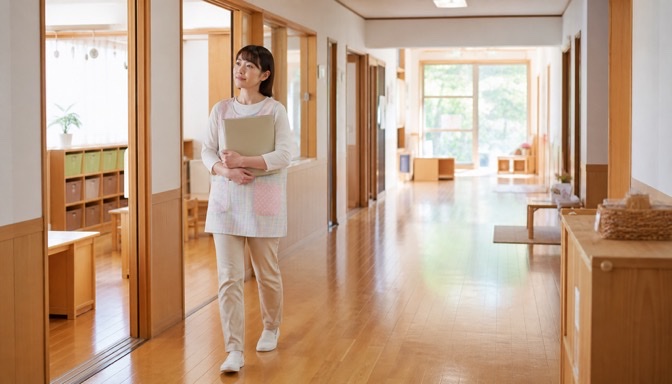 保育園の廊下を歩きながら将来を考える保育士